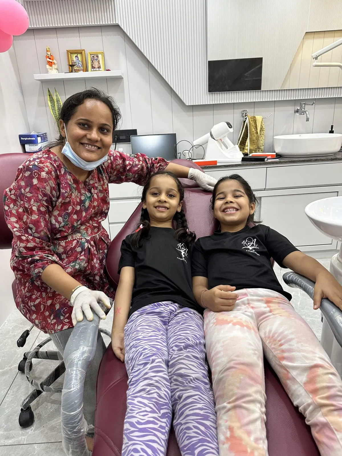 Dr. Rima Shah with two smiling young patients in the treatment chair